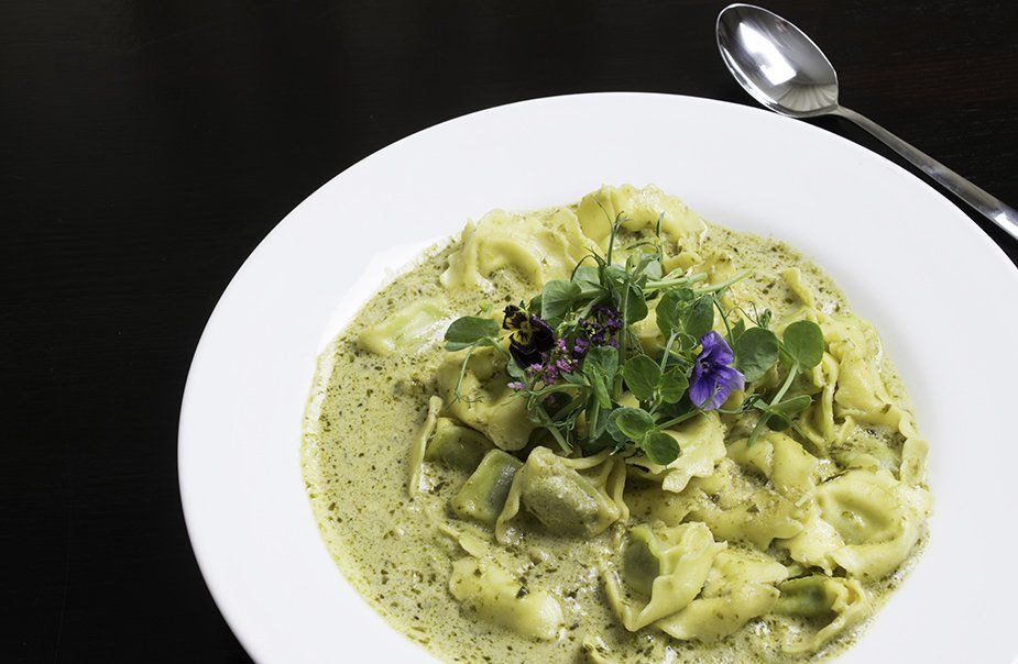 A white plate topped with pasta and a spoon on a table.
