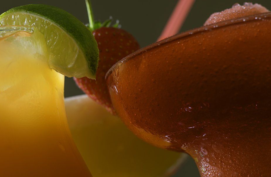 A close up of a margarita with strawberries and limes on a table.