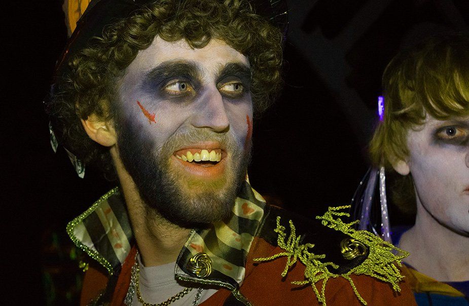 A man in a zombie costume is smiling while standing next to a child.