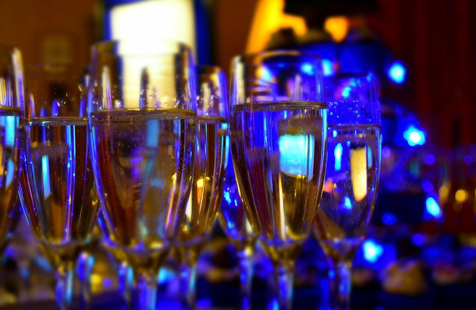 A row of champagne glasses on a table with blue lights in the background.