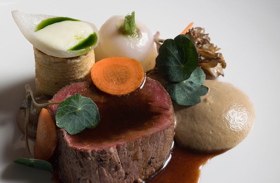 A white plate topped with a piece of meat and vegetables.