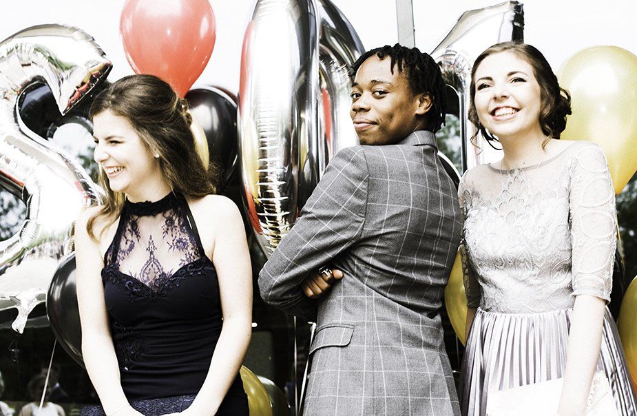 Three women are posing for a picture with balloons in the background.