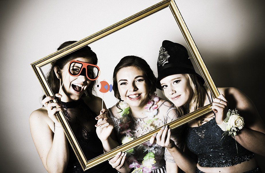 Three women are posing for a picture while holding a picture frame.