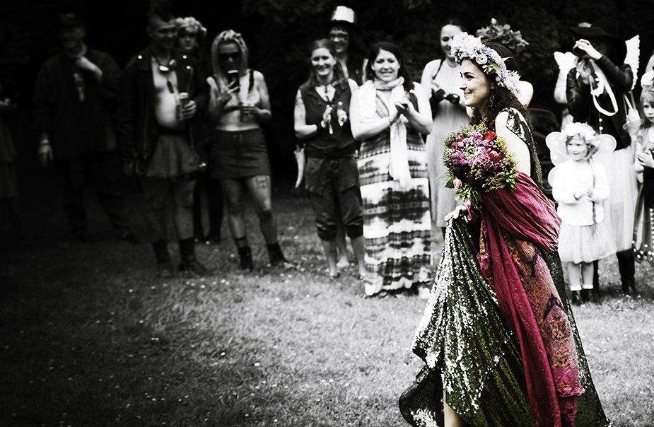 A woman in a red dress is holding a bouquet of flowers in front of a crowd of people.