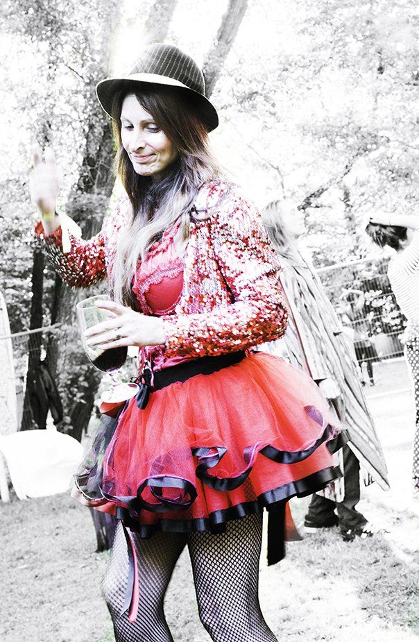 A woman in a red dress and hat is holding a drink