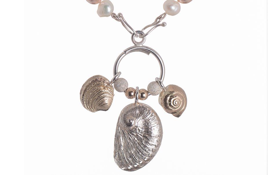 A close up of a necklace with shells and pearls on a white background.