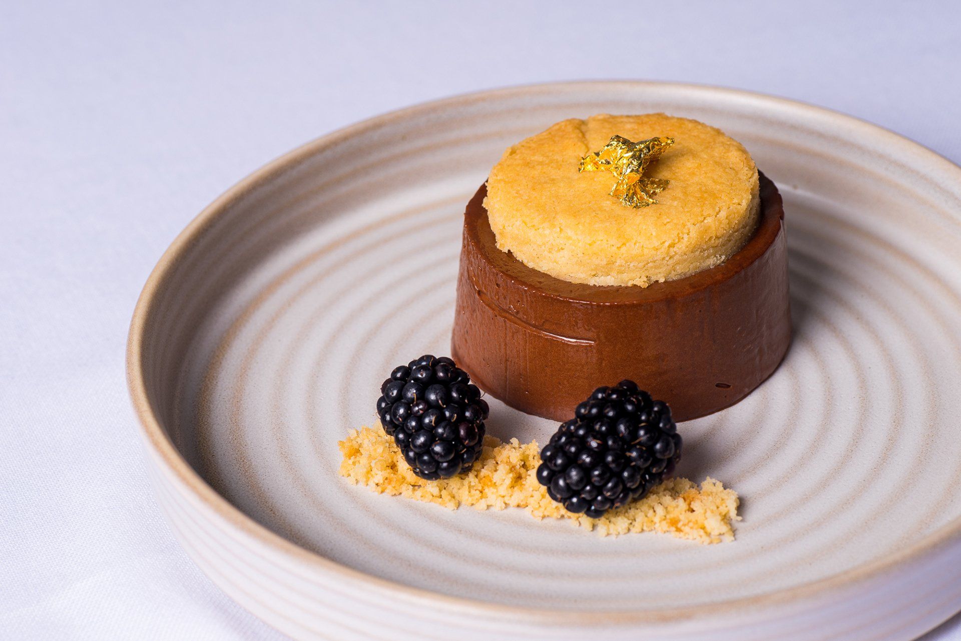 A white plate topped with a chocolate dessert and blackberries