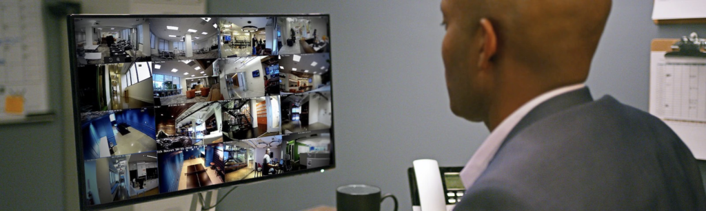 A man in a suit is looking at a monitor while talking on a phone.