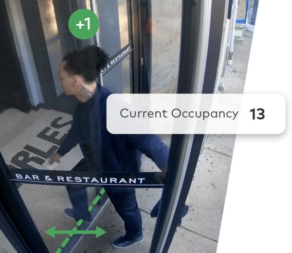 A man walking through a glass door with a current occupancy of 13