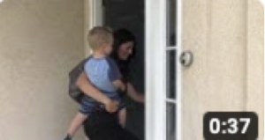 A woman is holding a baby in her arms while standing in front of a door.
