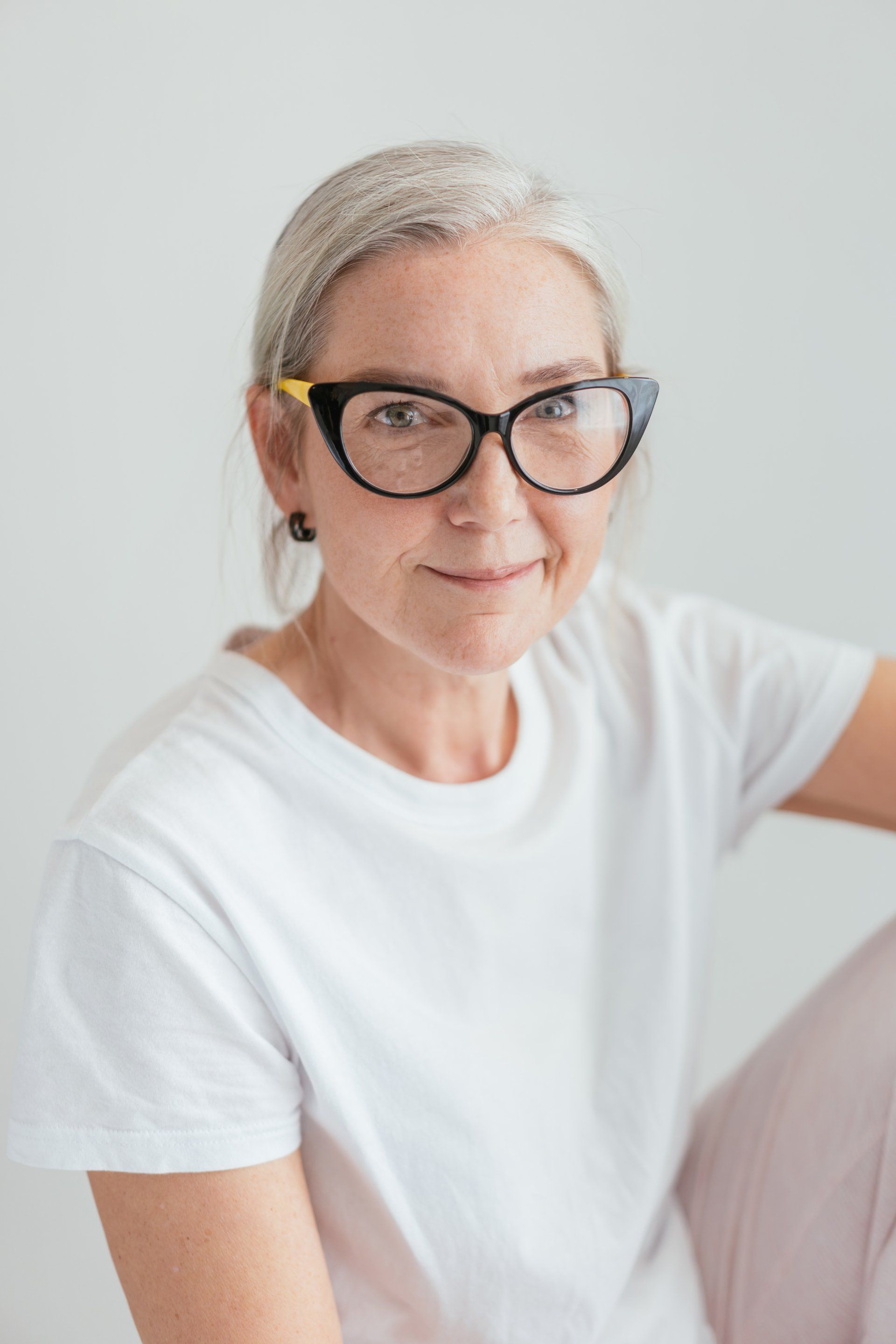 The woman is wearing glasses and a white t-shirt.