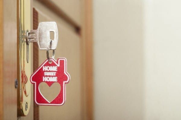 A key is hanging on a door with a keychain in the shape of a house.