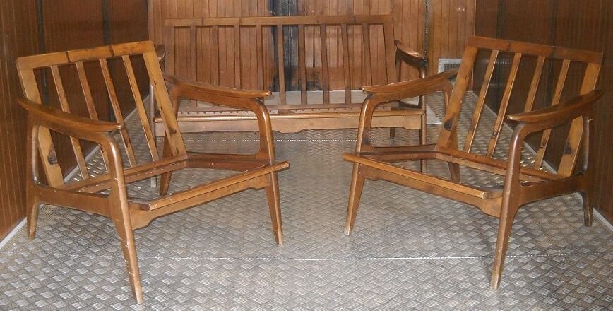 Due poltrone in legno e una panca coordinata in una stanza rivestita in legno.