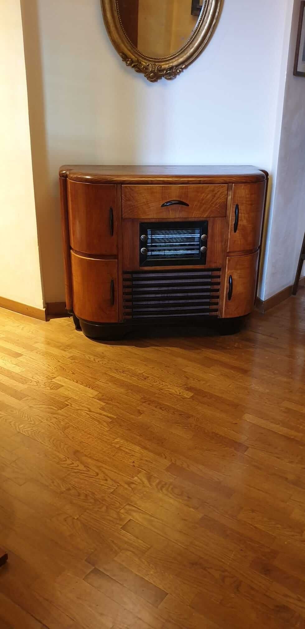 Mobile radio in legno con specchio sopra e pavimento in legno massello.