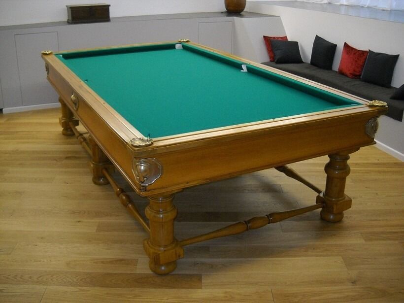 Tavolo da biliardo in legno con feltro verde in una stanza ben illuminata.