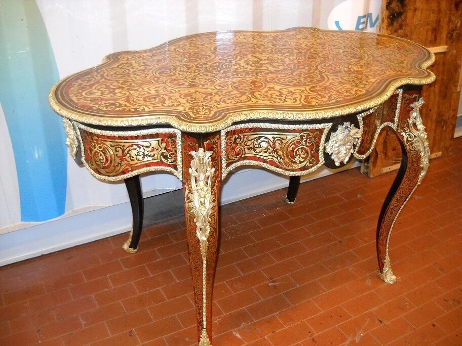 Tavolo antico decorato color mogano con intricati intarsi, bordi smerlati e dettagli dorati.