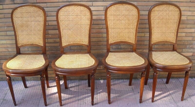 Quattro sedie vintage in legno con schienali e sedili in canna intrecciata.