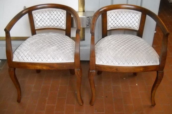 Due poltrone in legno con seduta e schienale in tessuto bianco fantasia.