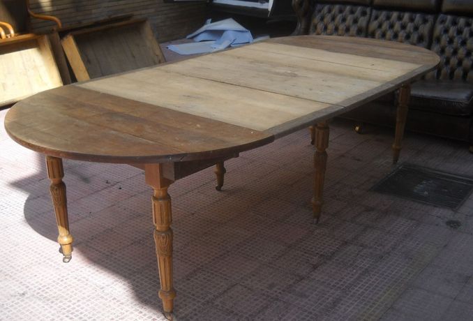 Tavolo da pranzo ovale in legno con gambe intagliate su un patio.