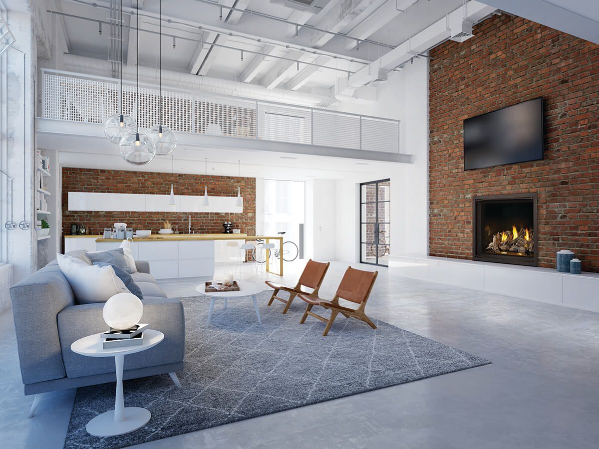 Un loft moderne à aire ouverte avec un canapé gris, un mur d'accent en briques, une cheminée, un coin repas et un balcon mezzanine blanc.