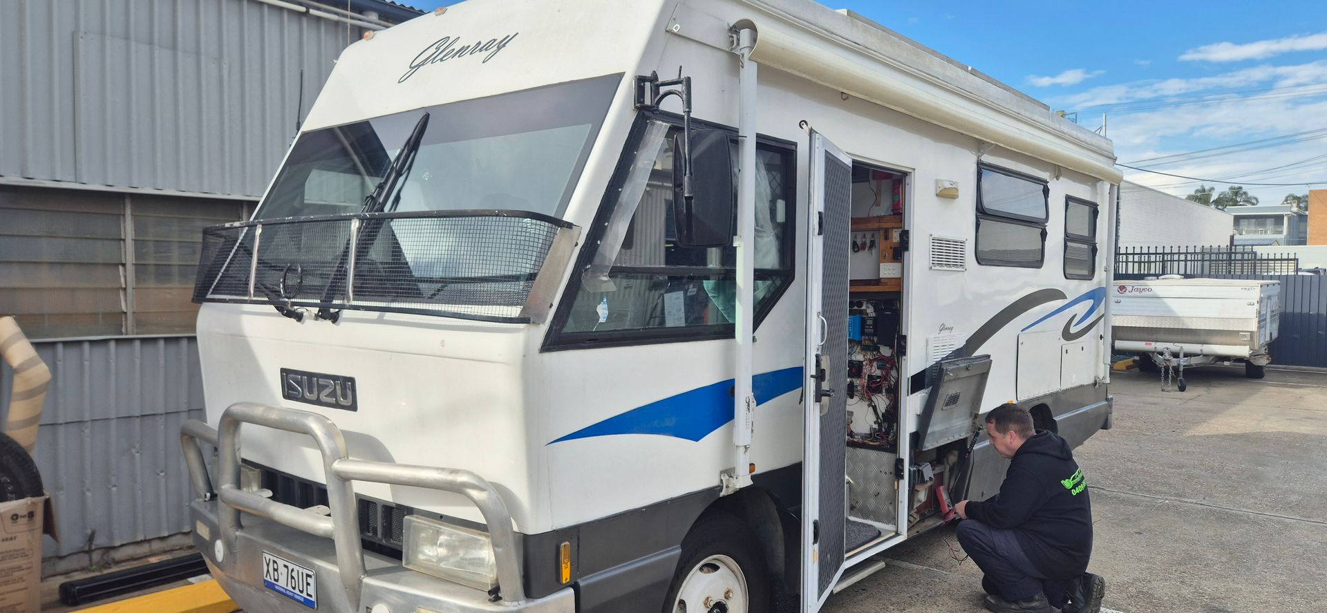 A Person Works on The Door of A White Rv — Revive Caravan Repairs in Kippa-Ring, QLD