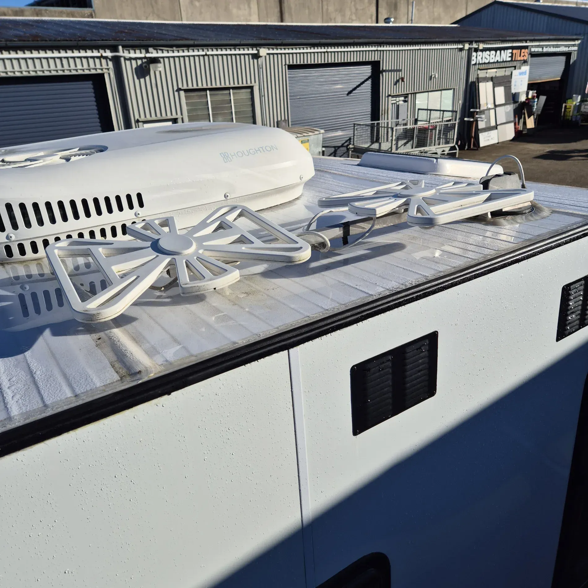 White roof of a vehicle with a satellite dome and various antennas against a commercial building background — Revive Caravan Repairs in Kippa-Ring, QLD
