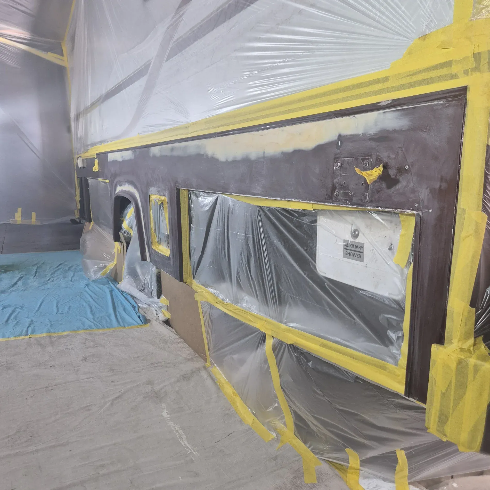 Vehicle side panel covered in plastic and tape, prepared for painting in a workshop — Revive Caravan Repairs in Kippa-Ring, QLD