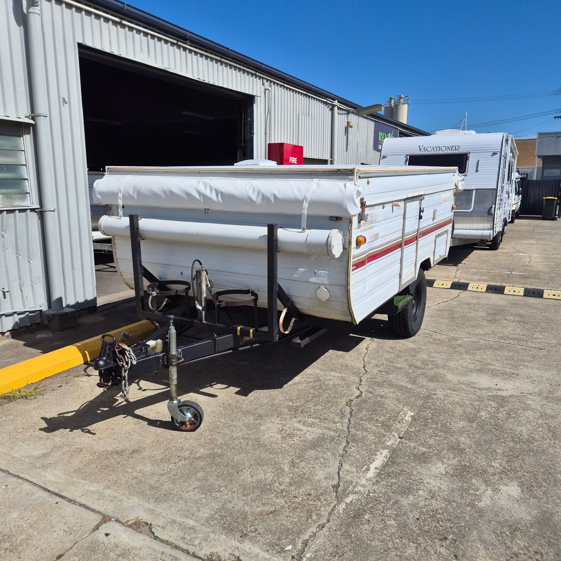 A Pop up Camper Trailer Parked Outside a Building on A Sunny Day — Revive Caravan Repairs in Kippa-Ring, QLD