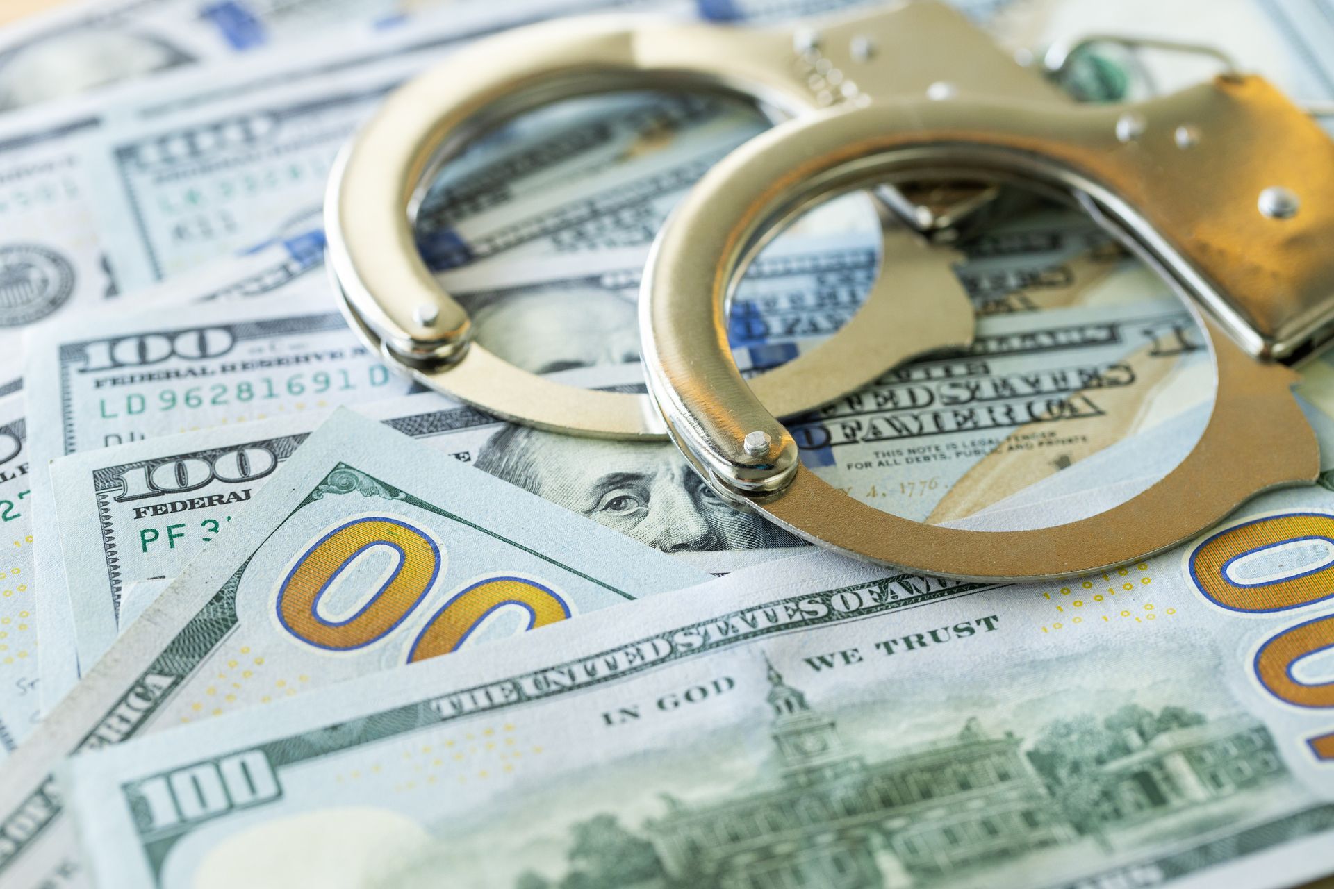Handcuffs on top of a pile of US $100 bills.