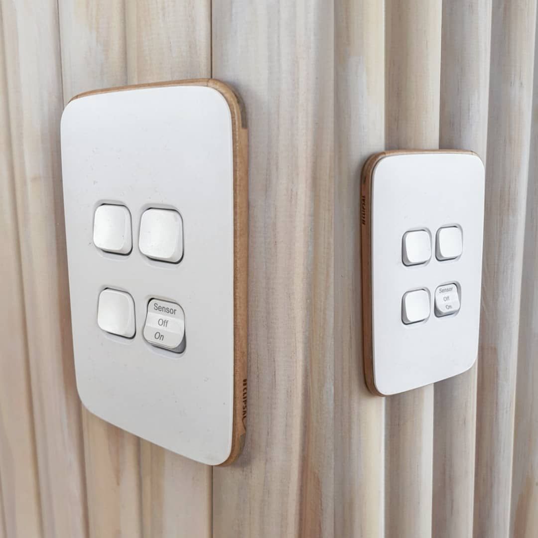 Two White Light Switches Are Mounted On A Wooden Wall — Electrician In Wagga Wagga, NSW