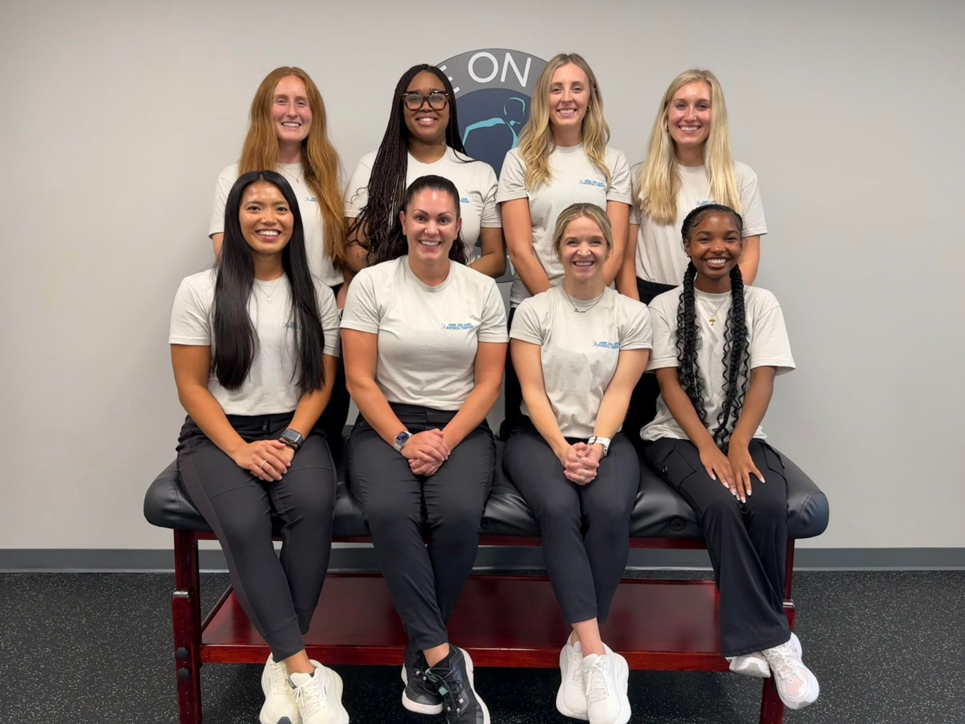 A group of women are posing for a picture while sitting on a table.