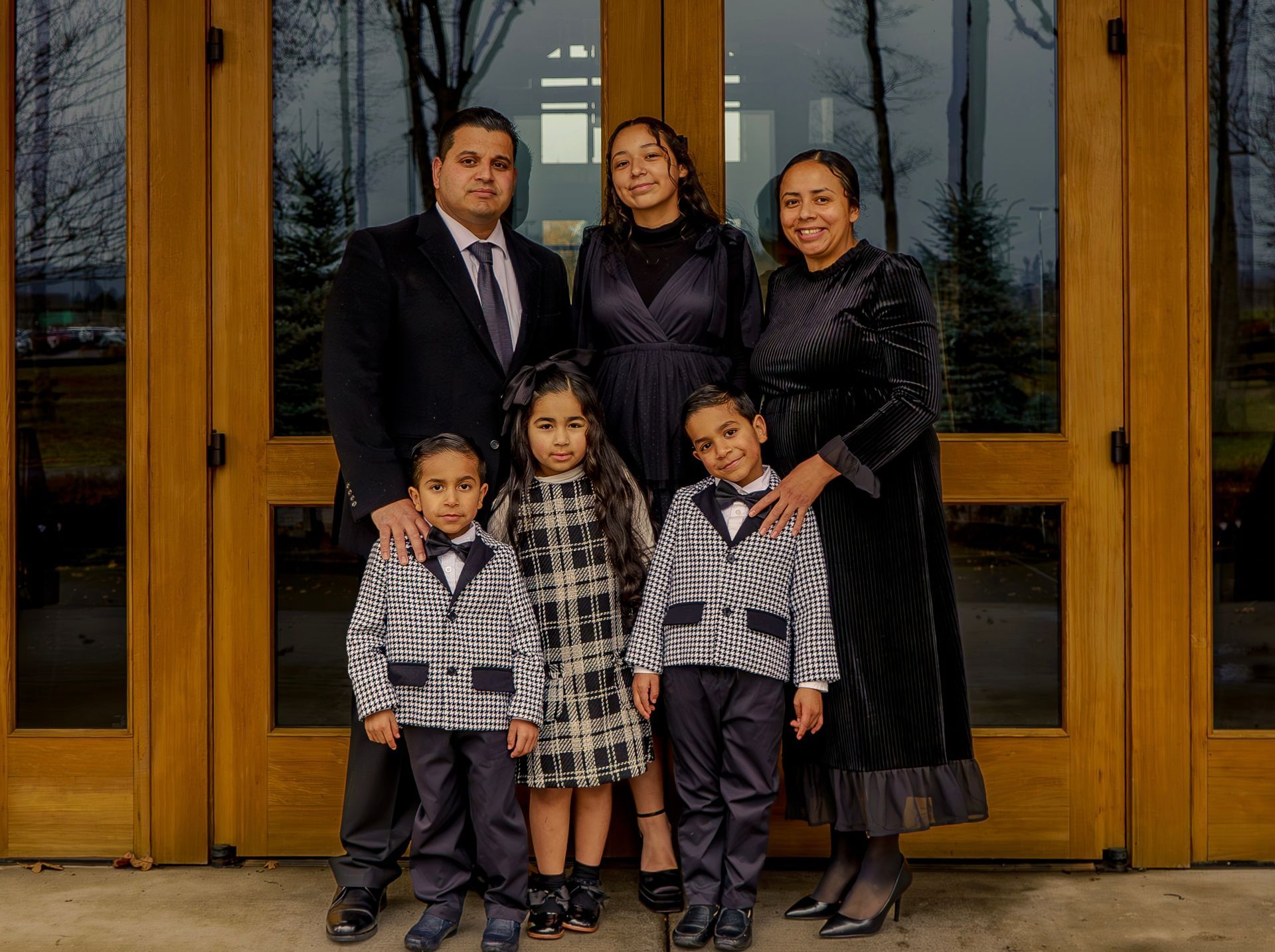 A family is posing for a picture in front of a wooden door.