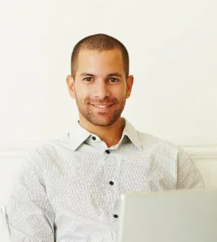 A Man is Sitting on a Couch Using a Laptop Computer — Hyde Burchell Buyers Agents In Canberra, ACT