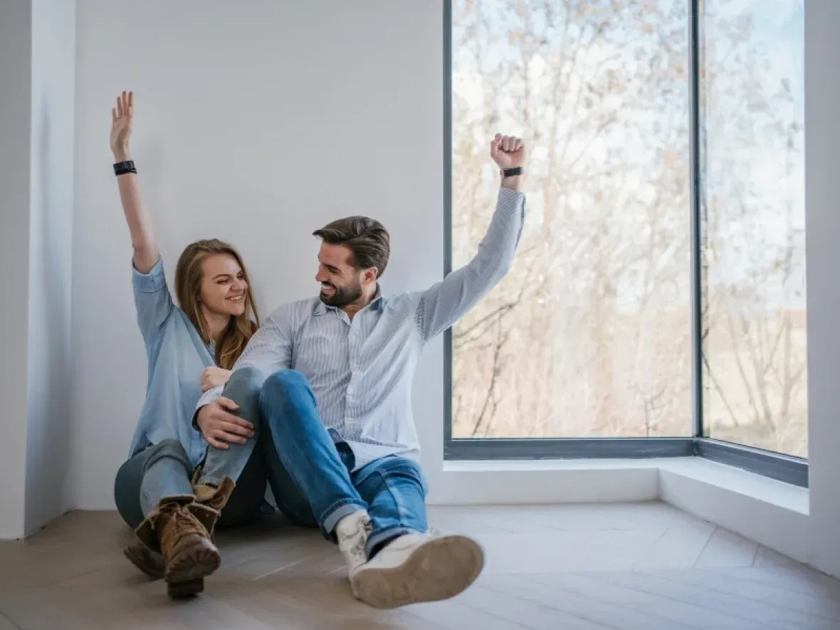 A Man and a Woman Are Sitting on the Floor in Front of a Window — Hyde Burchell Buyers Agents In Canberra, ACT