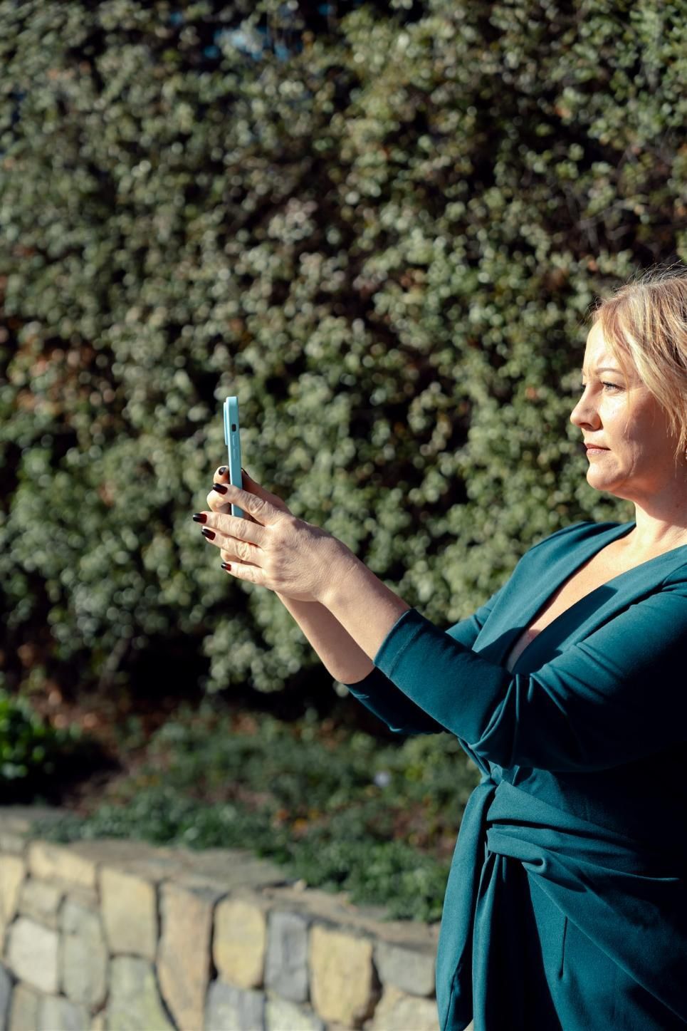 A Woman in a Blue Dress is Taking a Picture With Her Cell Phone — Hyde Burchell Buyers Agents In Canberra, ACT