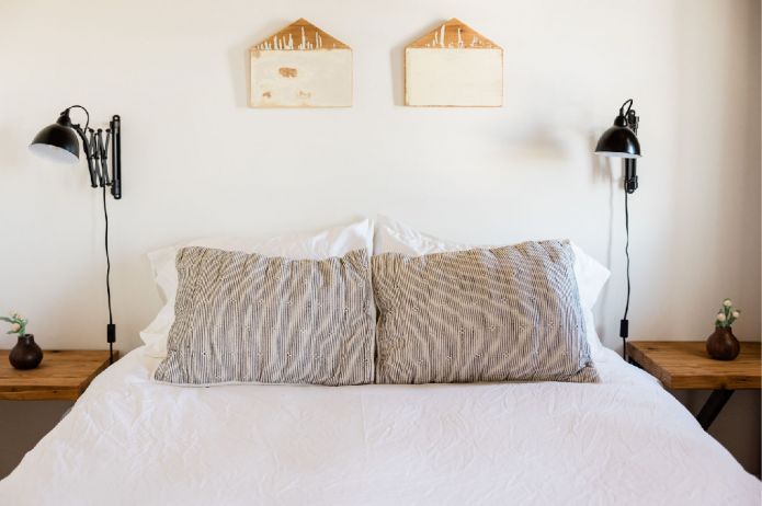 A Bedroom With a Bed and Two Paintings on the Wall — Hyde Burchell Buyers Agents In Canberra, ACT
