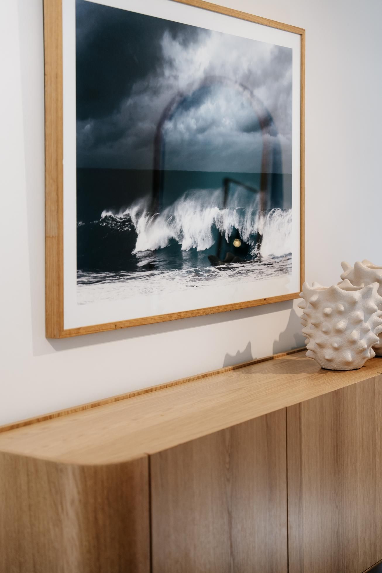 A Wooden Sideboard With a Framed Artwork and a Decorative Coral 