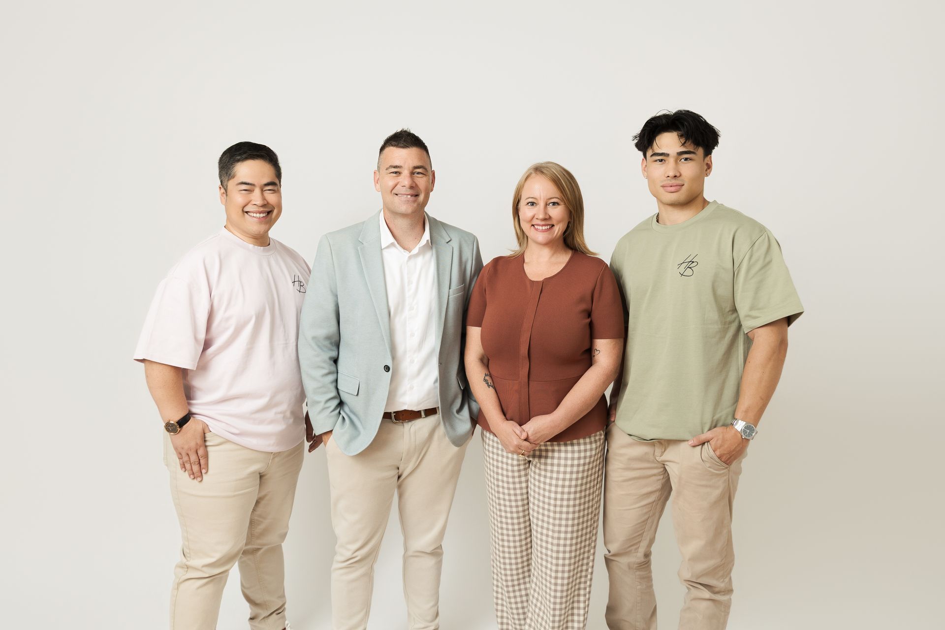 Four people standing together against a plain light background, smiling at the camera — Hyde Burchell Buyers Agents In Canberra, ACT