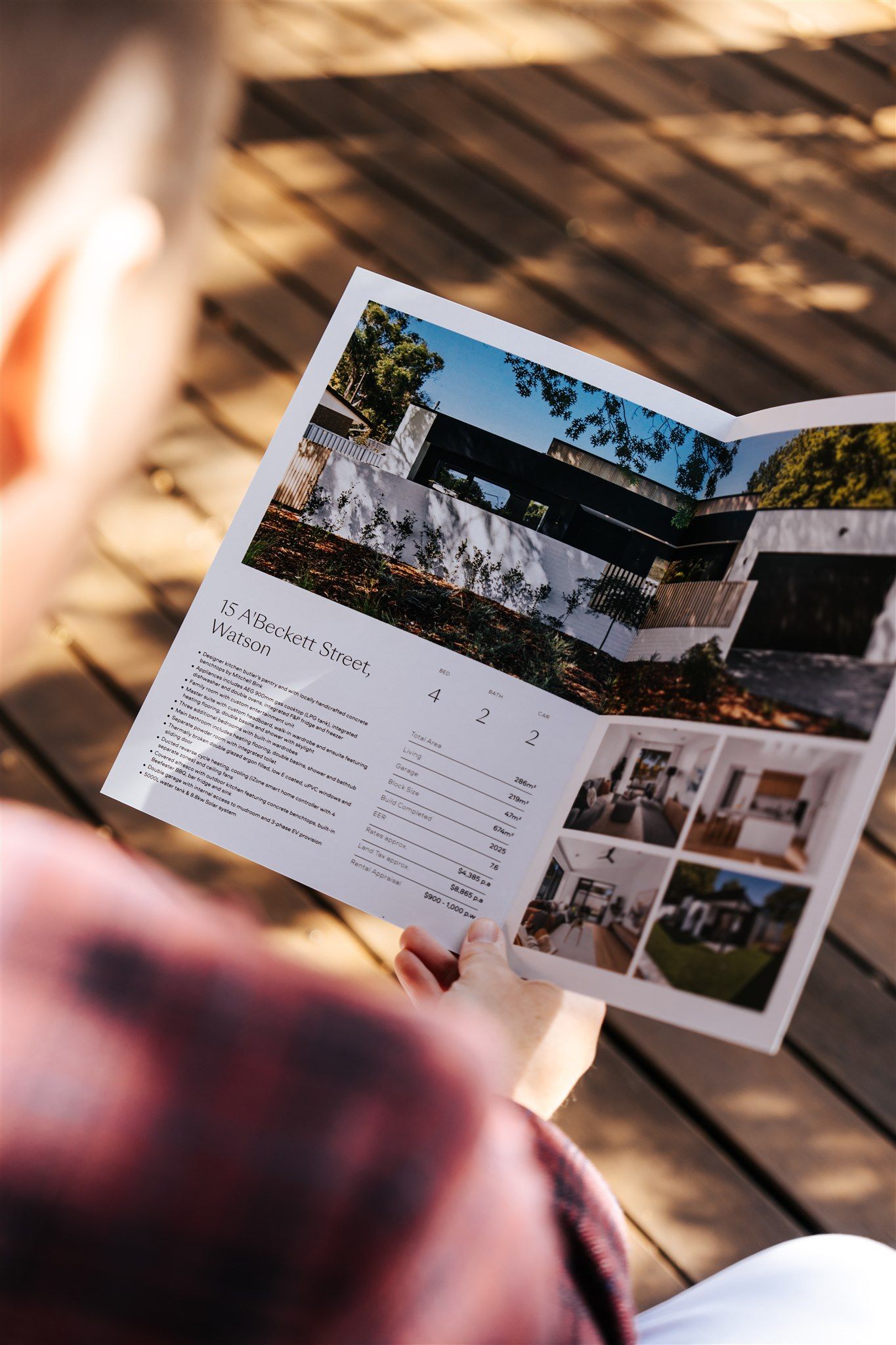 A Person is Holding a house pamphlet in their hand— Hyde Burchell Buyers Agents In Canberra, ACT