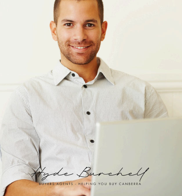 A Man in a White Shirt is Using a Laptop Computer — Hyde Burchell Buyers Agents In Canberra, ACT