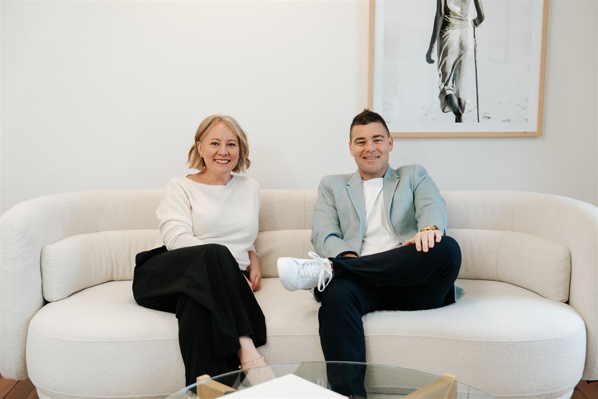 A Man and a Woman Are Sitting at a couch and Smiling — Hyde Burchell Buyers Agents In Canberra, ACT