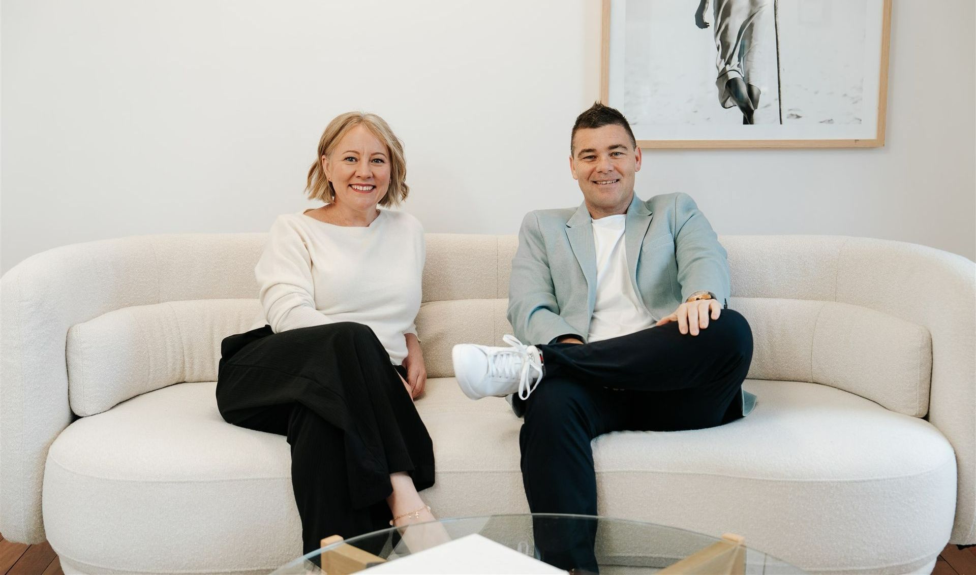 A Man and a Woman Are Sitting at a couch and Smiling — Hyde Burchell Buyers Agents In Canberra, ACT
