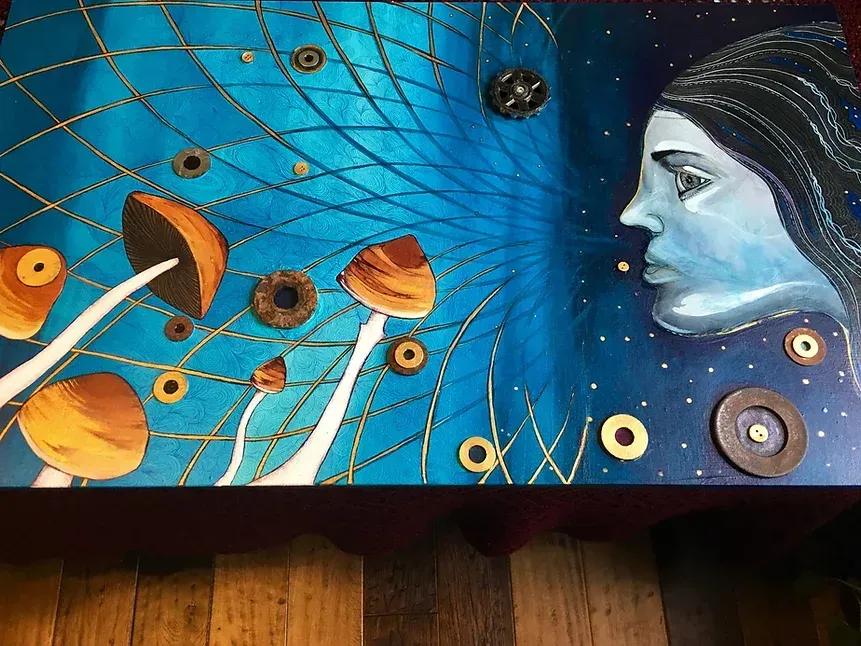Image of a woman's profile staring out over some magic mushrooms with an intricate energetic pattern in the background.
