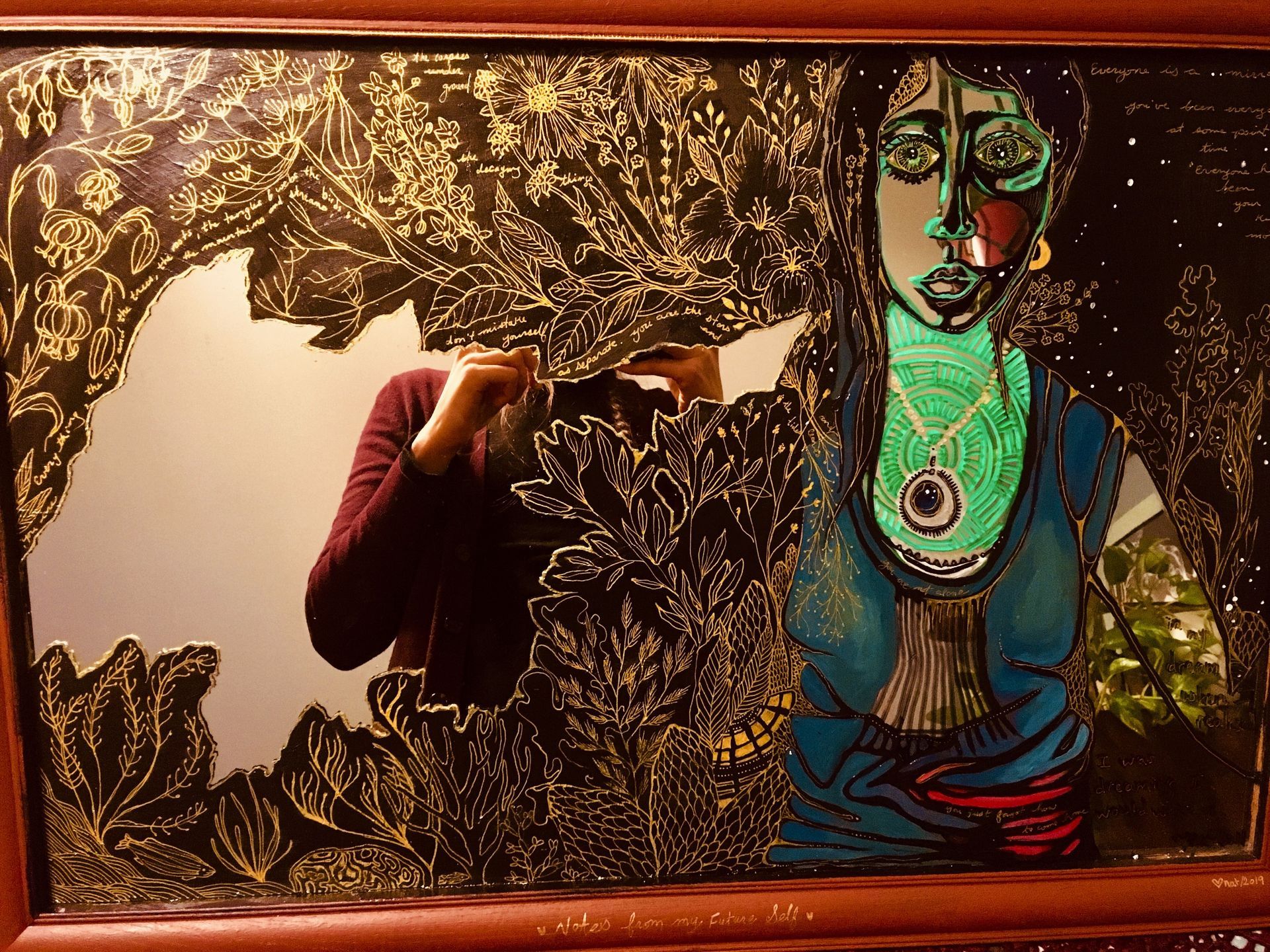 A painting of a woman with a vibrant heart-space, her arms outstretched, turning into both earth and sea plants  (black and gold).