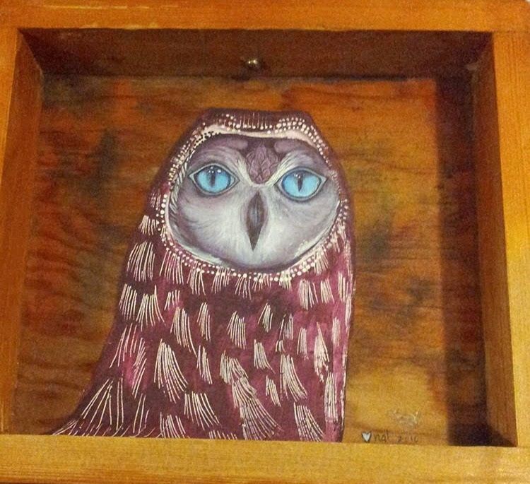 Painting of a brown owl with blue eyes with etched feathers carved into the back of a wooden drawer.