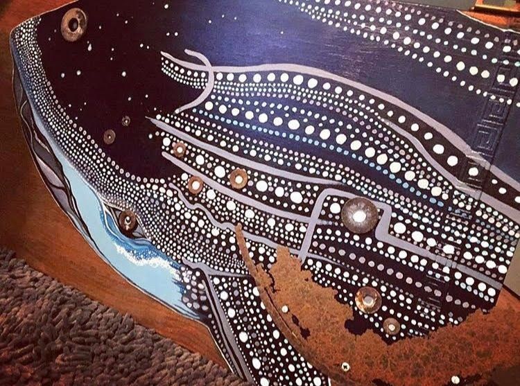 Painting of a whale with ,any white dots covering their body and rust as rougher skin.