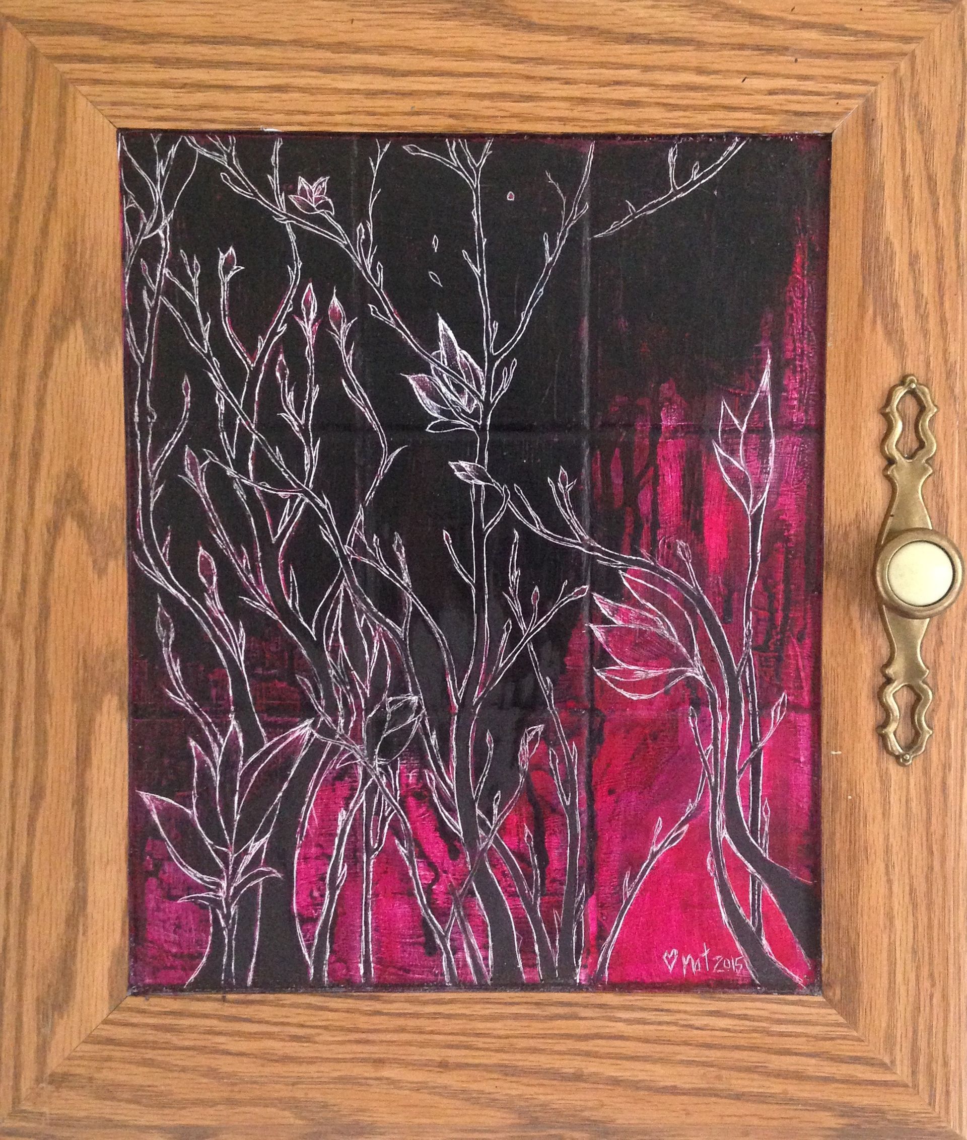 Painting of some flowers, etched into black and pink paint in the background of a square cupboard door.