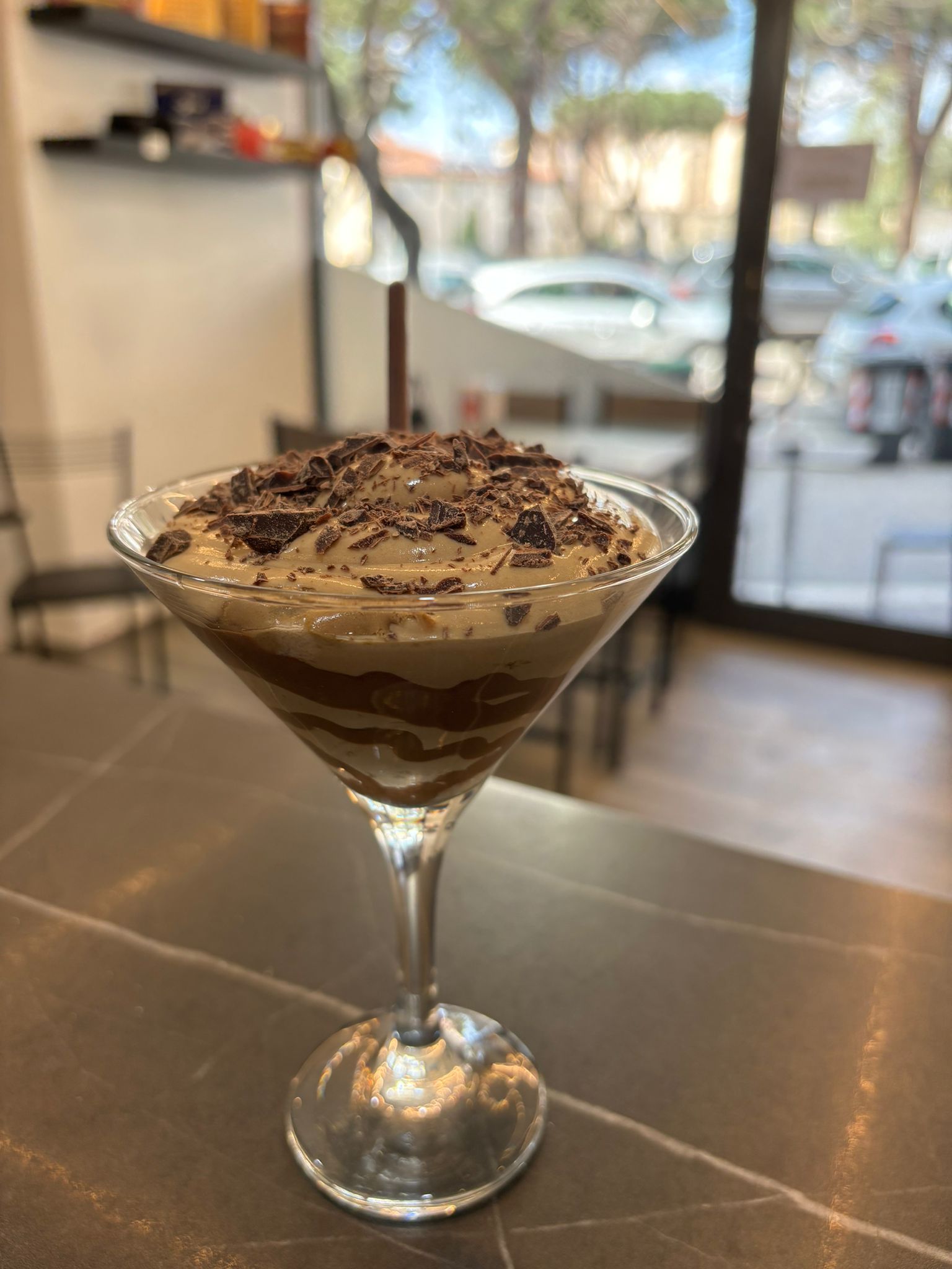 Una coppetta da martini riempita con un dessert con sopra scaglie di cioccolato.