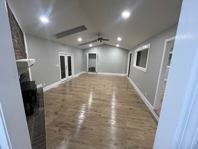 Empty living room with wood floor, recessed lighting, and brick fireplace.