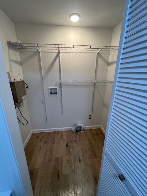Empty closet with wire shelving and wooden floor, door on right.